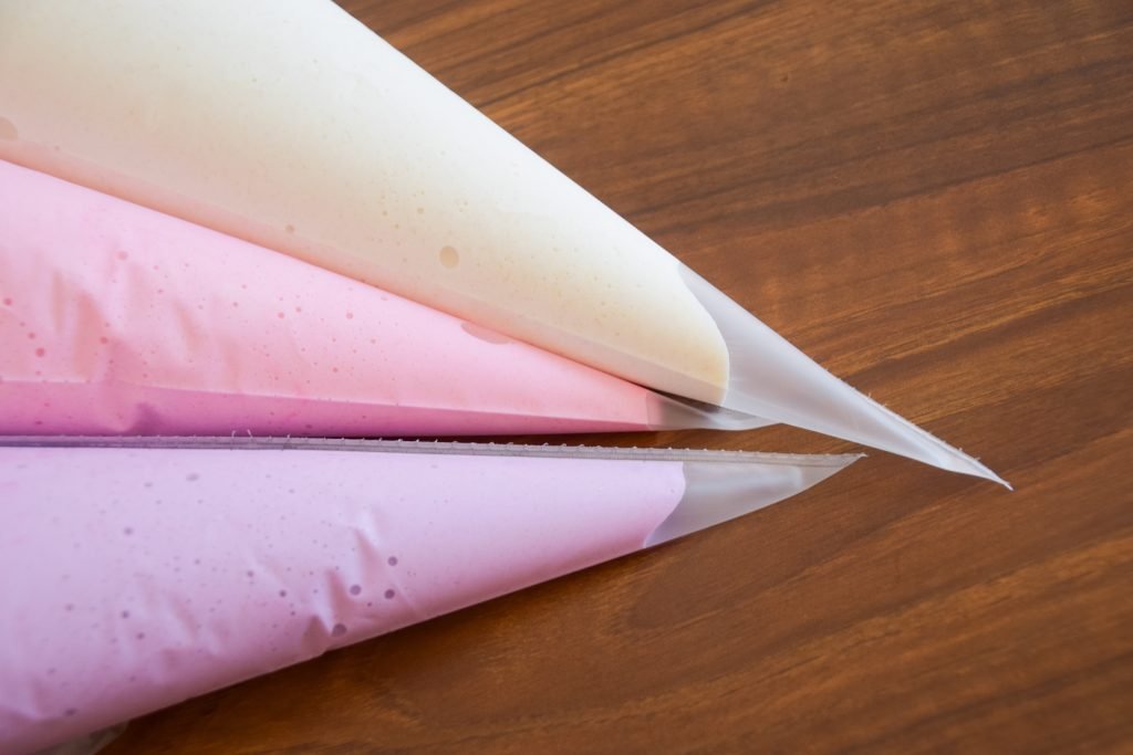 Pastel macaron batters in the piping bags