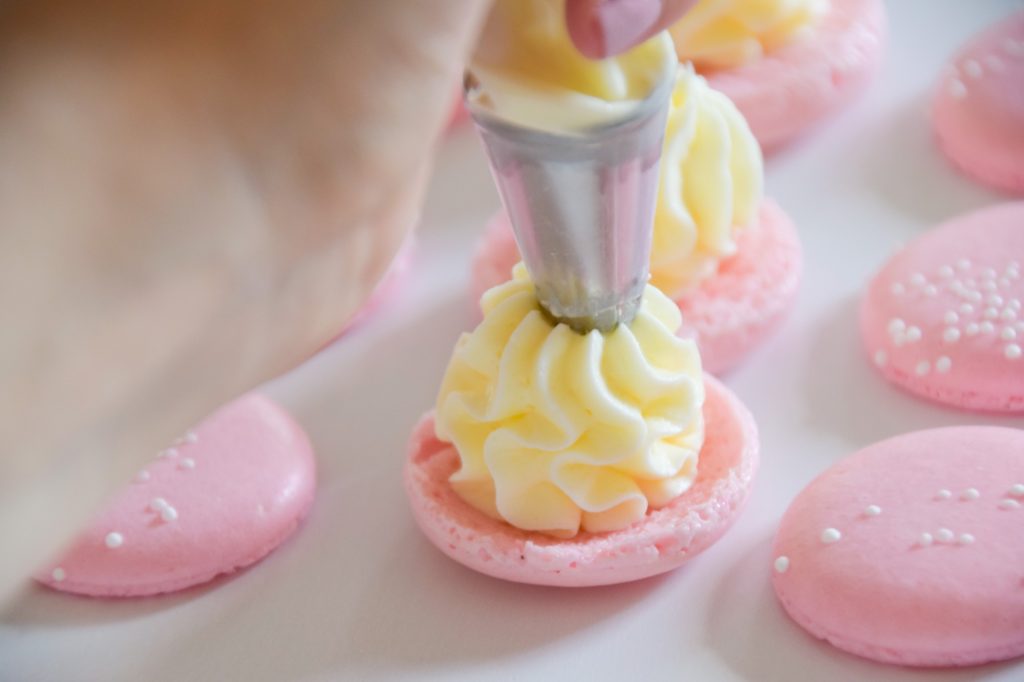 Filling the light pink champagne macarons ruffle style