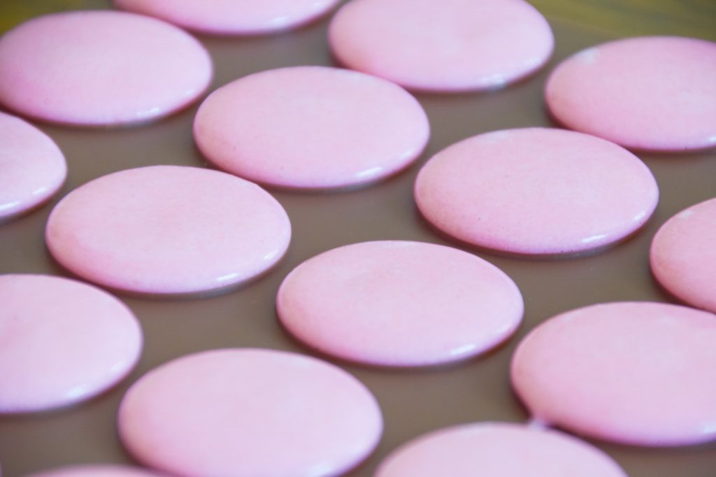 Pink macarons piped to the silicone mat