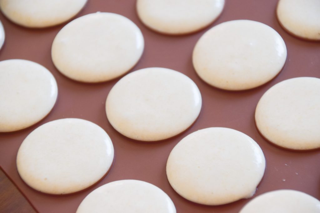 White macarons piped into the silicone mat