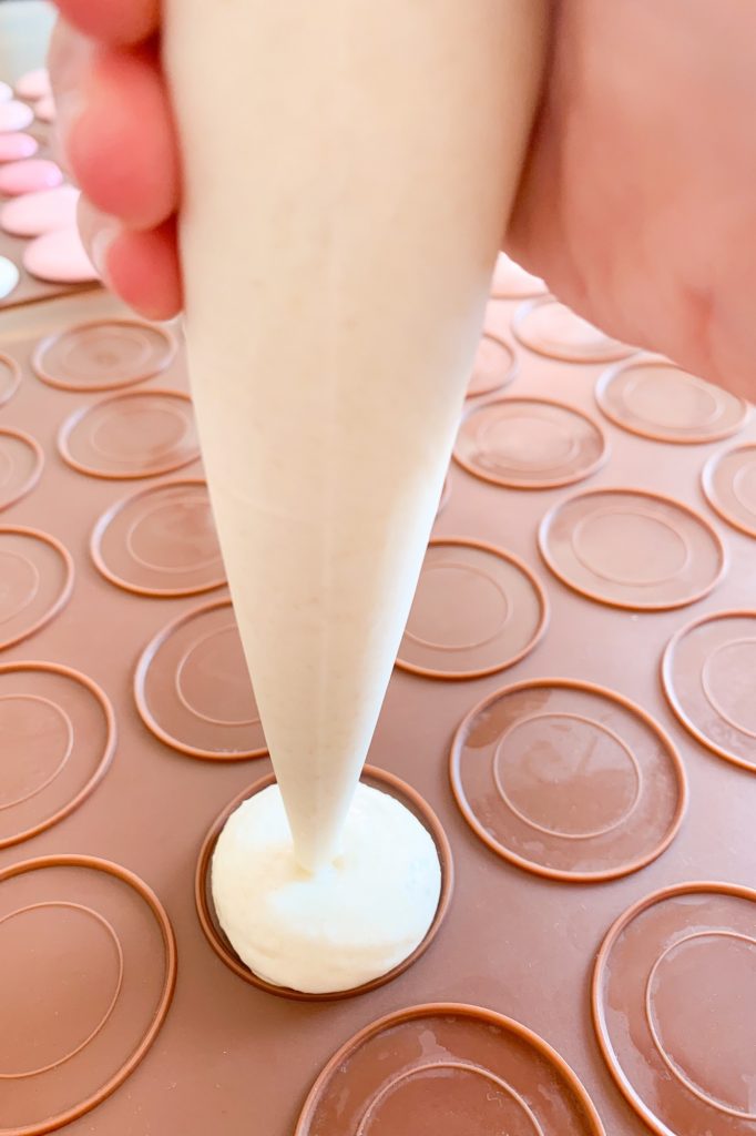 Piping the white macaron batter to the silicone mat