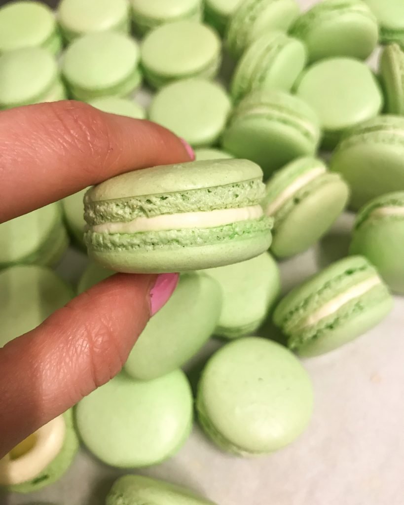 Perfect green pistachio macarons between fingers