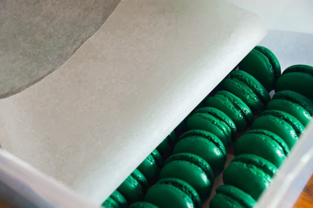 Packing dark green macarons into an airtight container