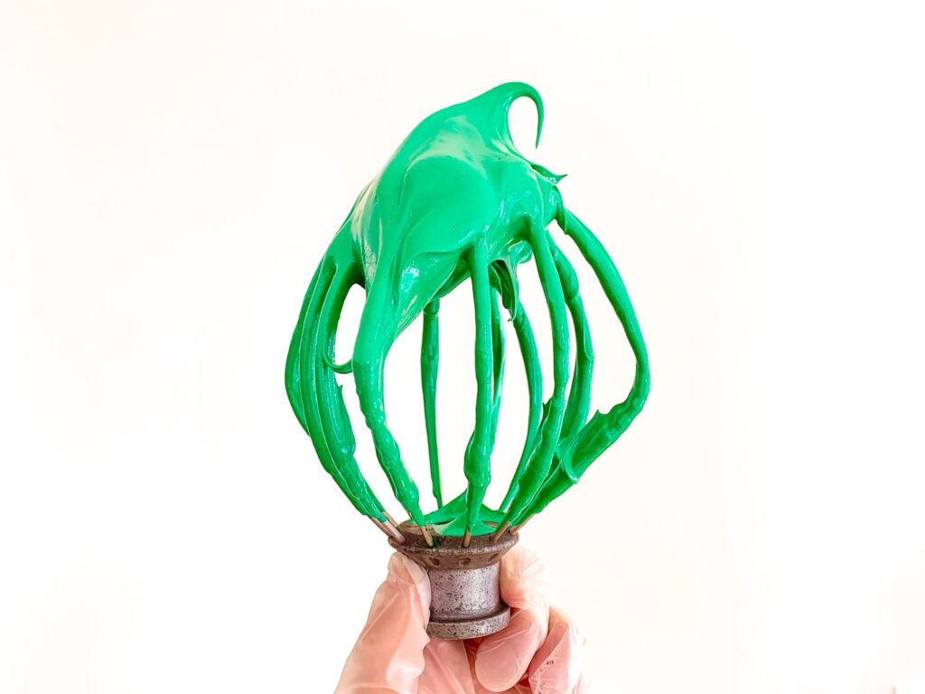 Kitchen Aid whisk covered in green macaron batter