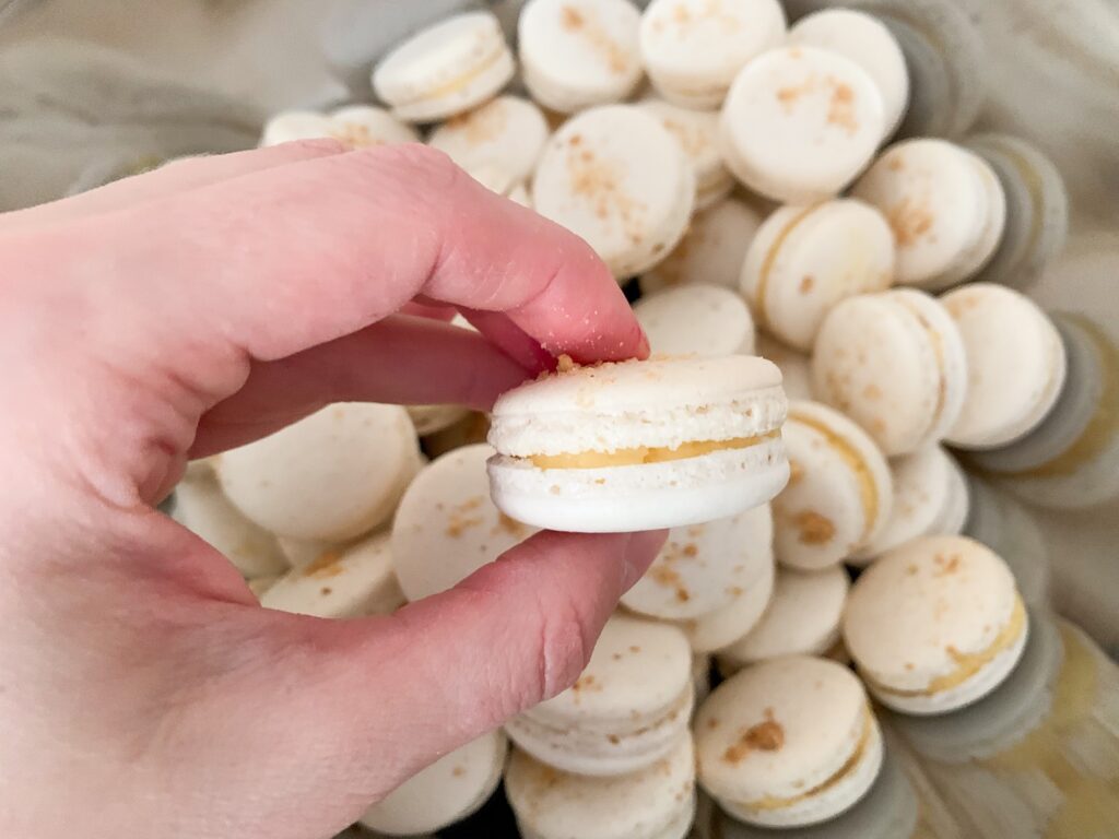 White salted caramel macarons between fingers