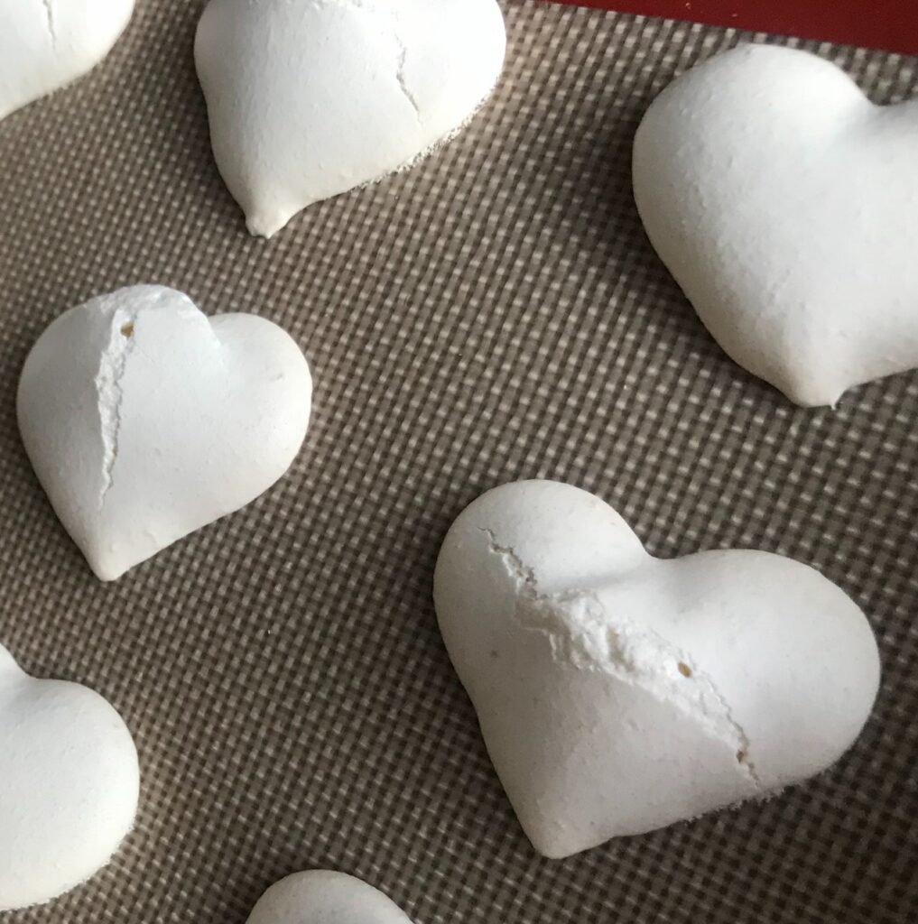 White exploded heart-shaped macaron shells with cracks