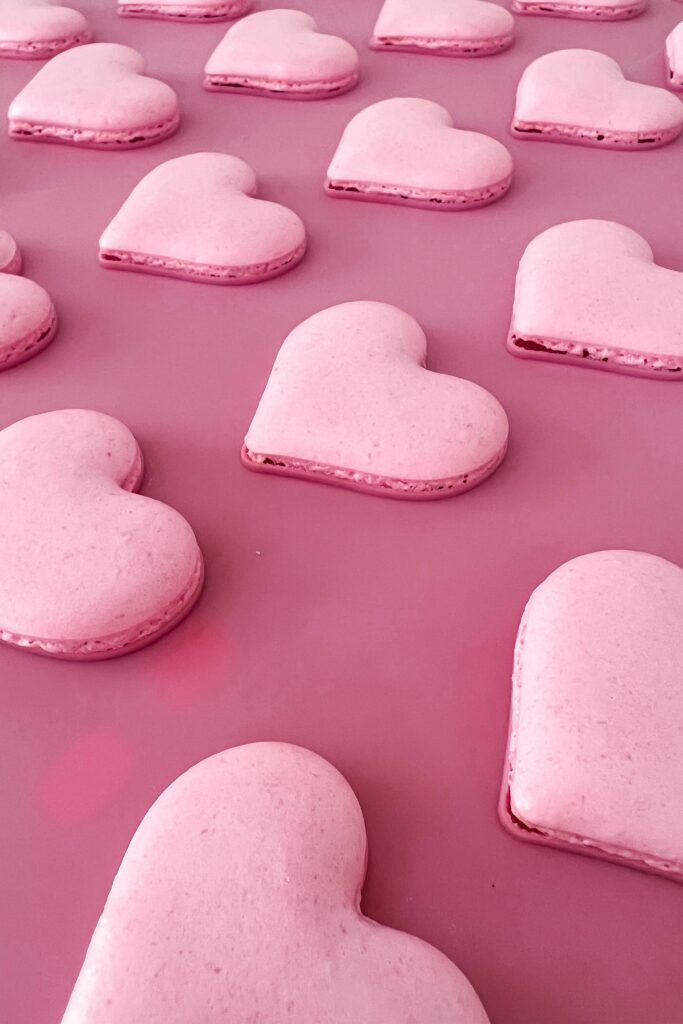 Pink heart-shaped macarons on silicone mat