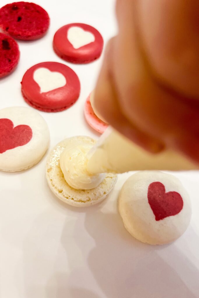 Piping filling between macaroon shells with hearts